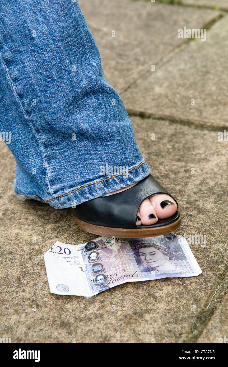 Close up dei womans piede su una ventina di Sterling Pound nota, concetto di perso e trovato, o fortunati. Foto Stock