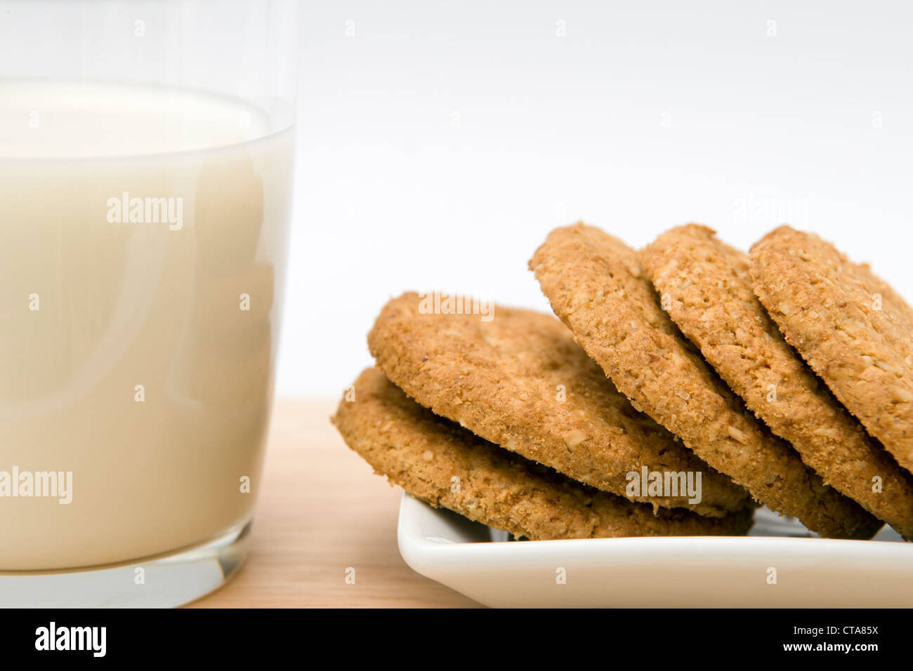 Un bicchiere di latte con piastra di biscotti su sfondo bianco Foto Stock