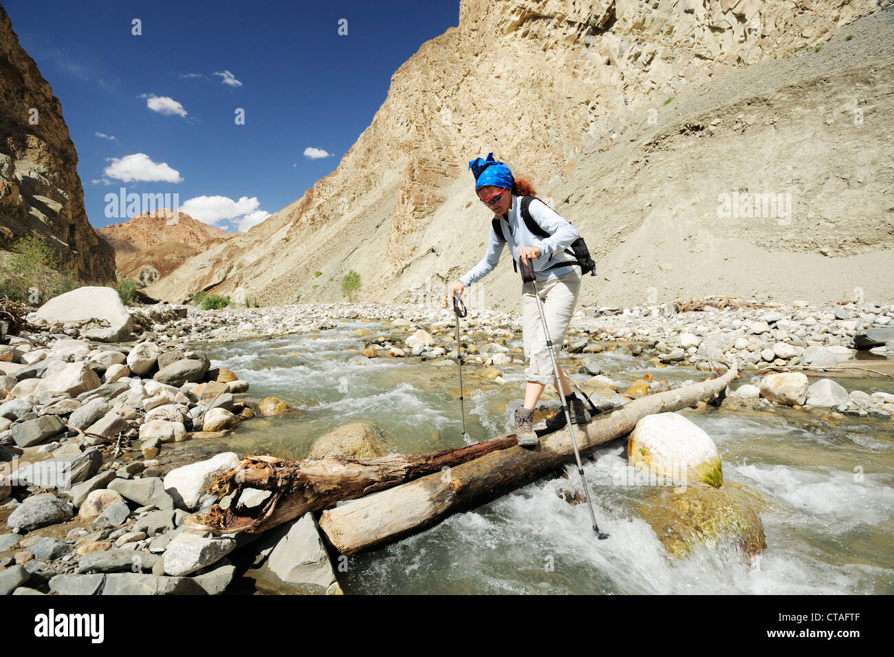 Donna Varcando il fiume su un tronco, discesa da Yangtang a Rizong, Ladakh, Jammu e Kashmir India Foto Stock