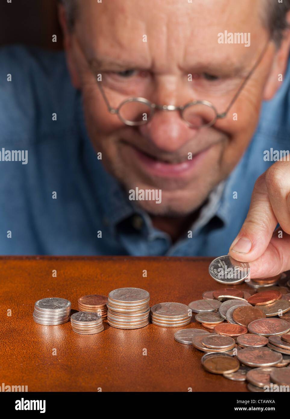 Senior pensionati uomo caucasico counting out cash in pile Foto Stock