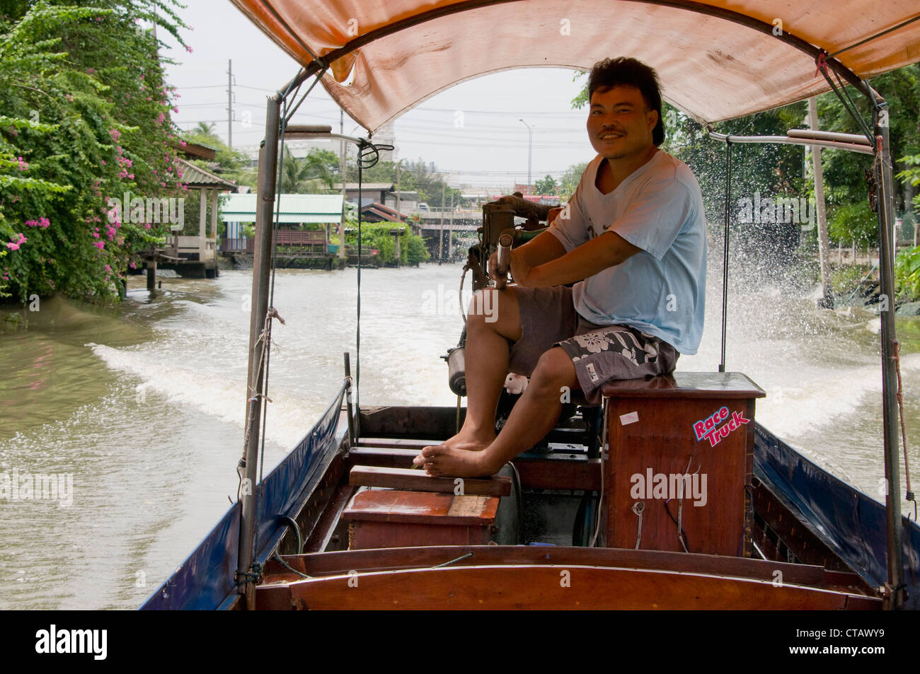 Un capitano al timone di una lunga coda di barca su Bangkok Yai canal a Bangkok, in Thailandia Foto Stock