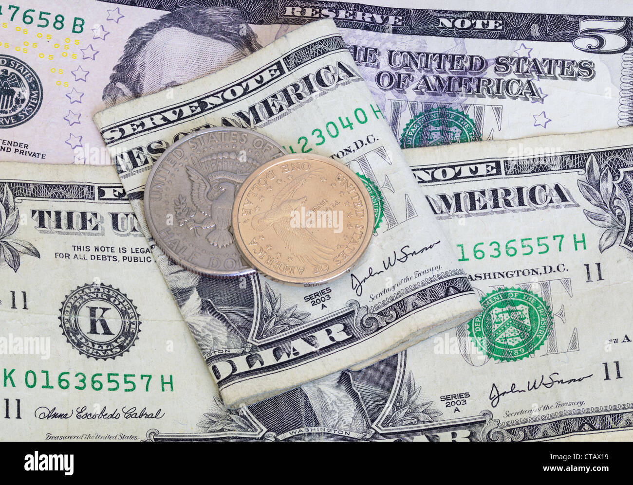 Il contrasto del dollaro e mezzo dollaro moneta con una carta usurata bill Foto Stock