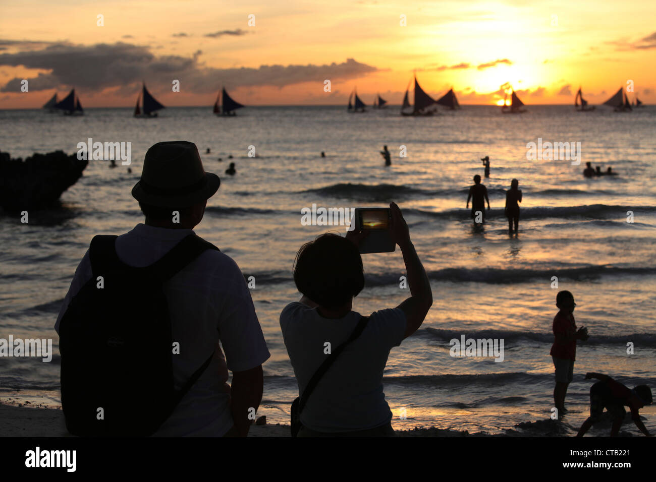 Due turisti fare foto al tramonto, Boracay, Panay Island, Visayas, Filippine Foto Stock