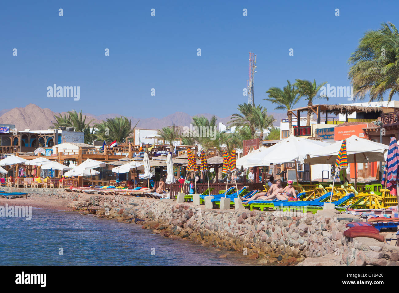 Vista sul mare della baia di Dahab con vacanzieri relax su lettini , Dahab, Egitto Foto Stock