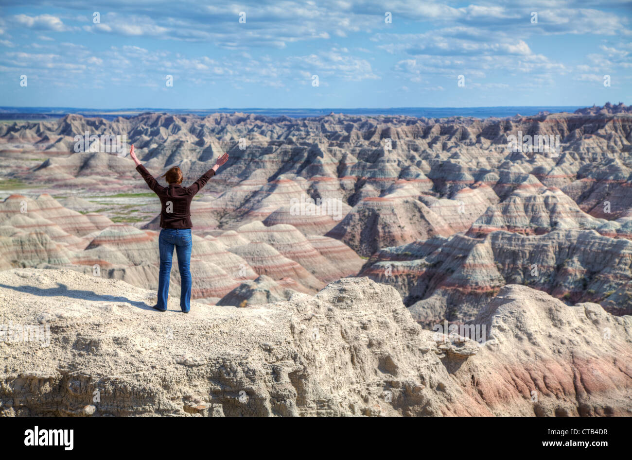 Donna con le mani alzate contro il paesaggio del terreno Foto Stock