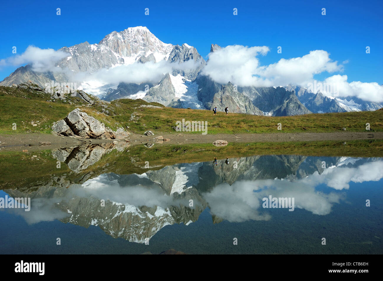 Vista sud volto Mont Blanc mountain range riflessa nel lago mentre due escursionisti a piedi lungo il percorso della Val Veny Italia Foto Stock