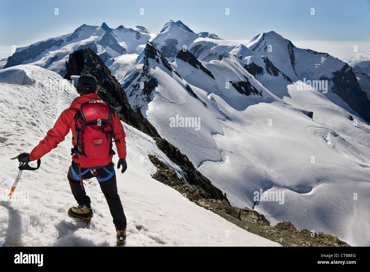 Alpinista passeggiate lungo il crinale nevoso Breithorn esattamente su swiss-confine italiano IIn sfondo picchi principali Monte Rosa massiccio Foto Stock