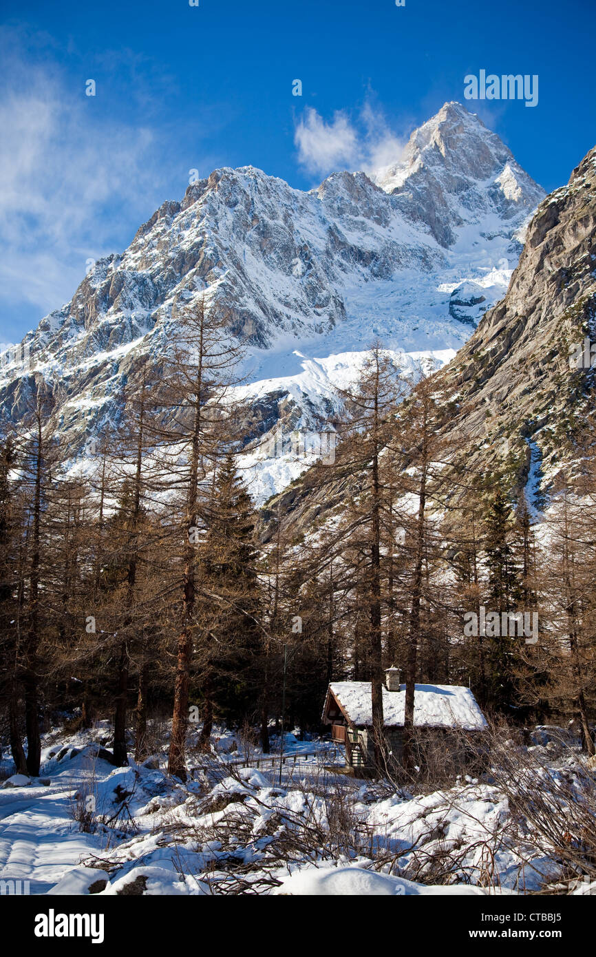 Paesaggio di montagna piccolo cottage in inverno bosco di larici in background di alta montagna Grand Jourasses Mont Blanc italiano Foto Stock