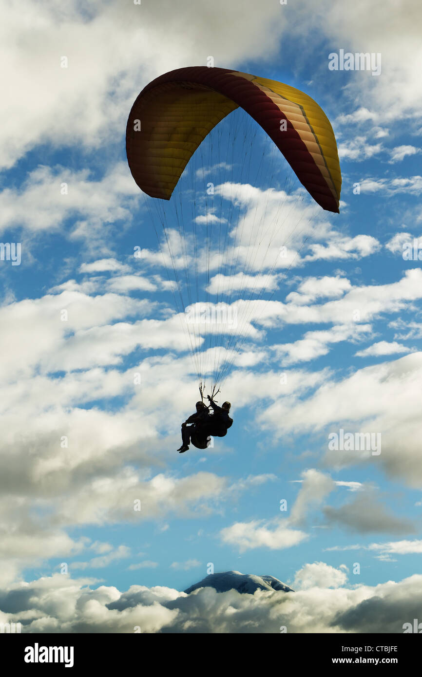 Parapendio in tandem contro il cielo nuvoloso Ande ecuadoriane in background Vulcano Chimborazo Foto Stock