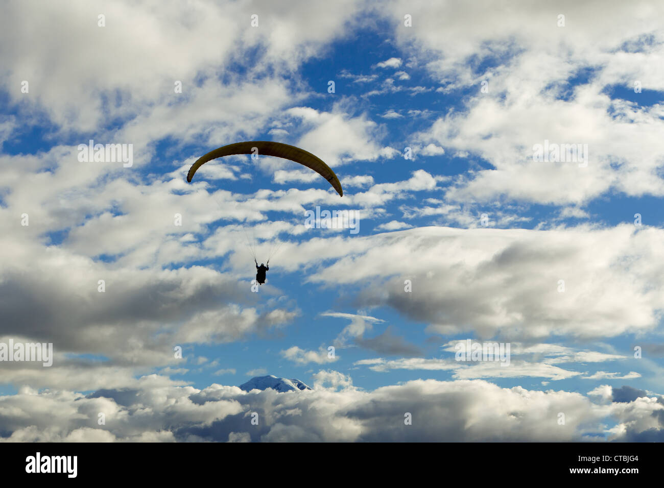 Parapendio in tandem contro il cielo nuvoloso Ande ecuadoriane in background Vulcano Chimborazo Foto Stock