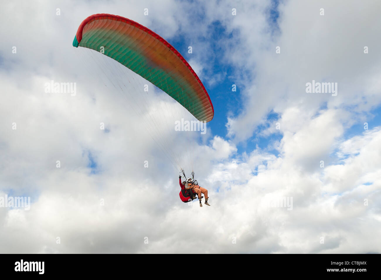 Il parapendio in tandem con il passeggero anteriore e il pilota nel retro indossando un paracadute di sicurezza Foto Stock