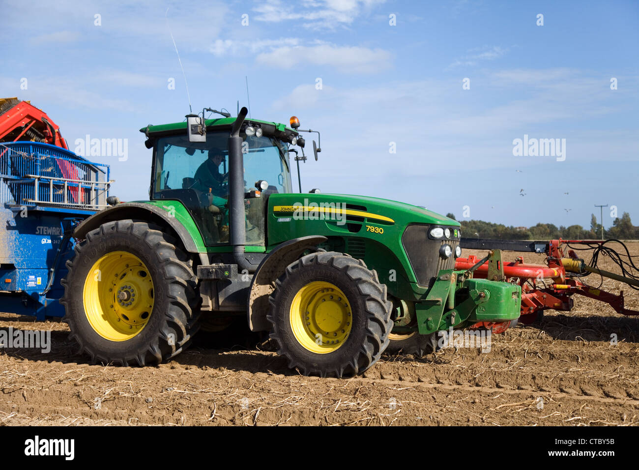 John Deere trattore 7930 & Stewart GX20-24Z rimorchio durante il raccolto di patate in Norfolk su una soleggiata giornata splendente. Foto Stock