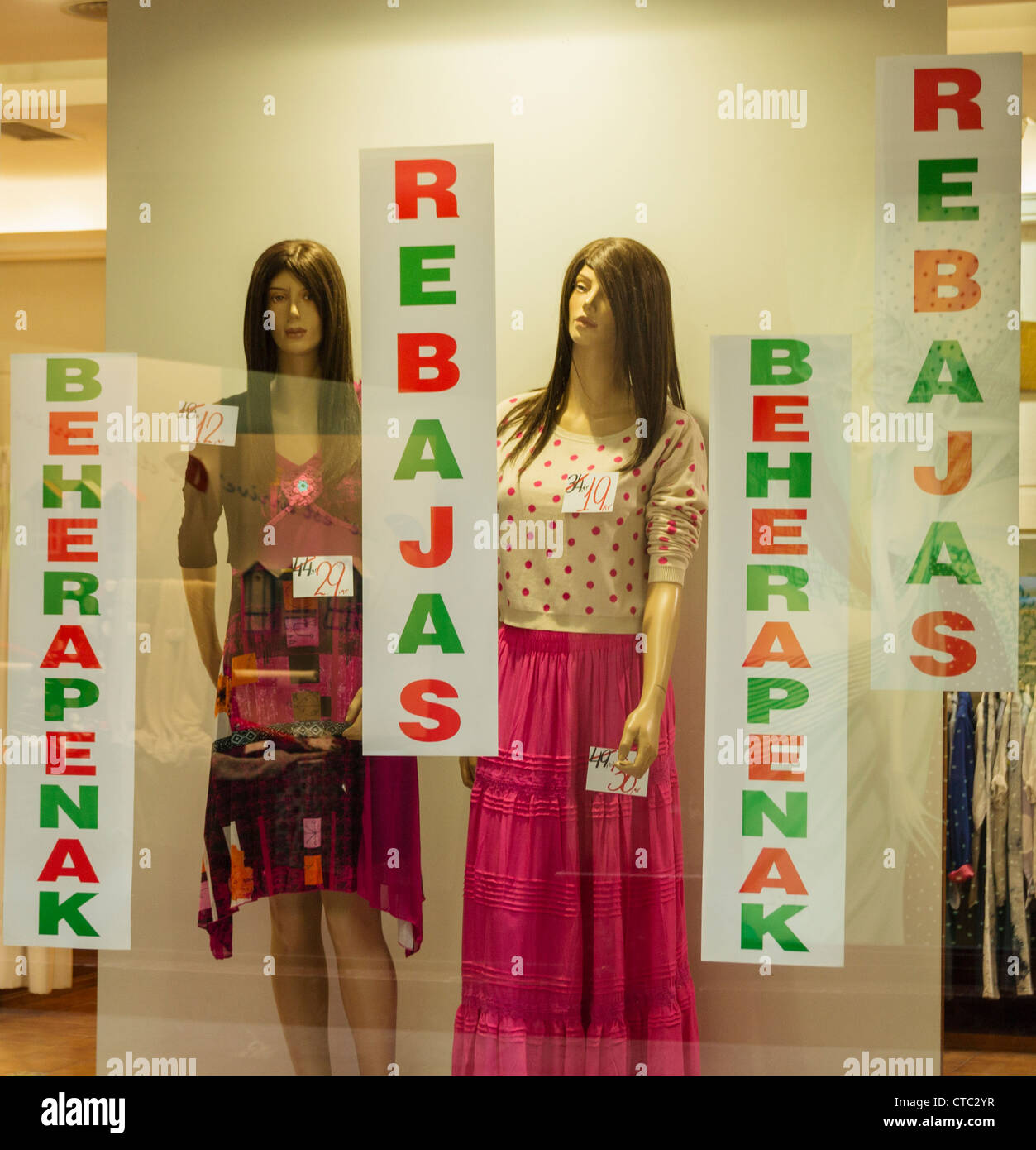 Vendita sign in spagnolo (Rebajas) e Euskera (Beherapenak), Paese Basco lingua in vetrina a Bilbao, SSpain Foto Stock