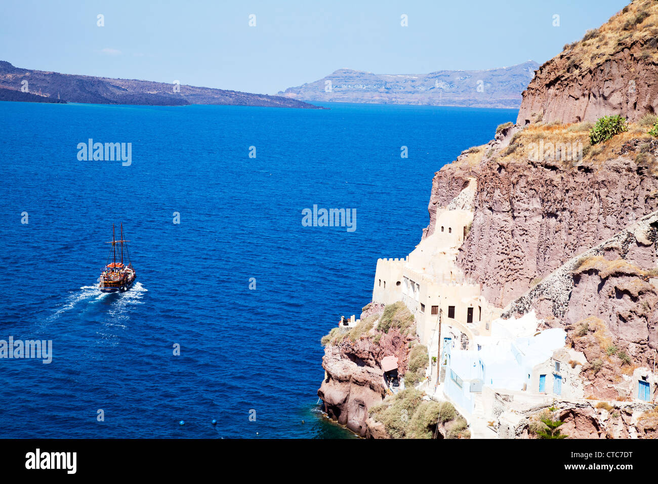 Barca a Vela passa case costruite nella roccia a Thira, Santorini, isola greca, grecia, sulla Caldera Foto Stock