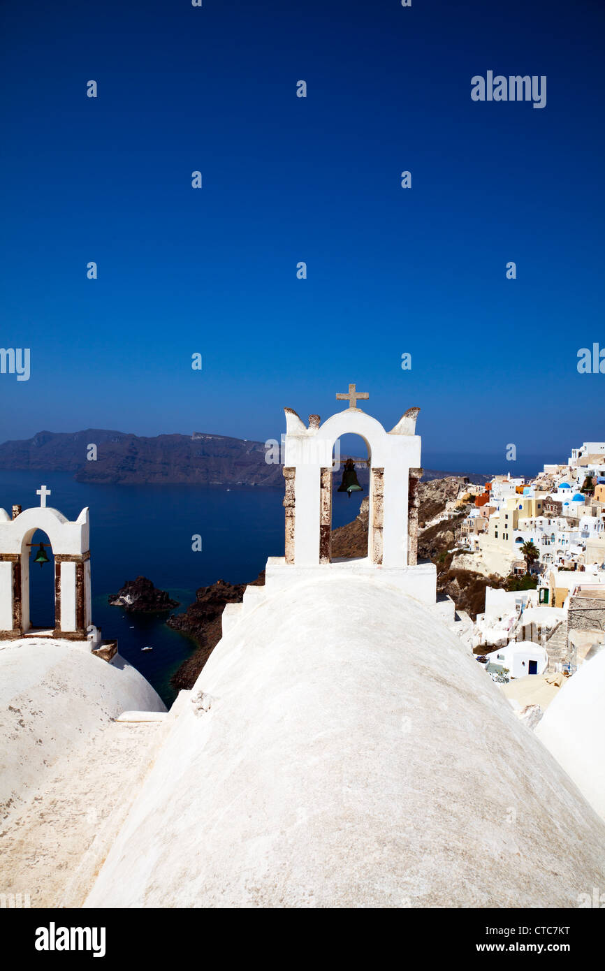 Oia - Santorini, isola greca, grecia, strano le campane della chiesa che si affaccia su caldera cicladi blu cielo nuvoloso Foto Stock