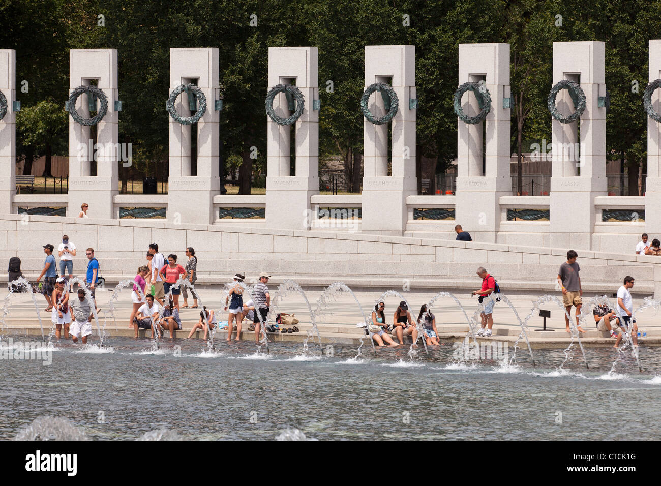 Visitatori dunk i loro piedi nella fontana, trovando rifugio dal caldo estivo, mentre la visita al Memoriale della Seconda guerra mondiale Foto Stock