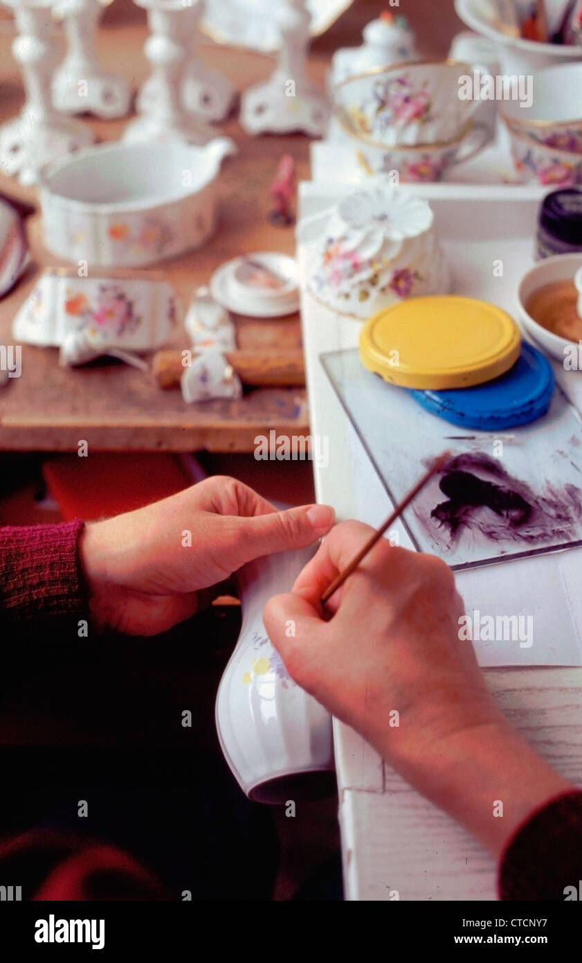 Un artista presso la fabbrica di porcellana dipinge un diciottesimo secolo scena su una piastra di porcellana. Tutti i disegni qui sono dipinti a mano. Foto Stock