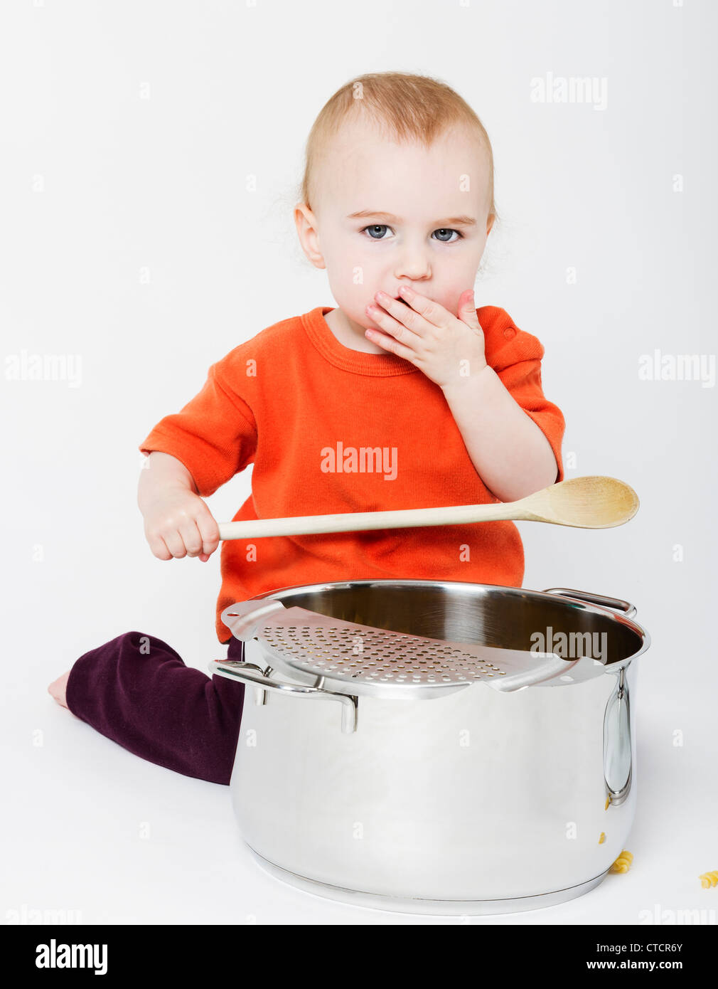 Bambino con grande pentola di cottura e il cucchiaio di legno su sfondo neutro Foto Stock