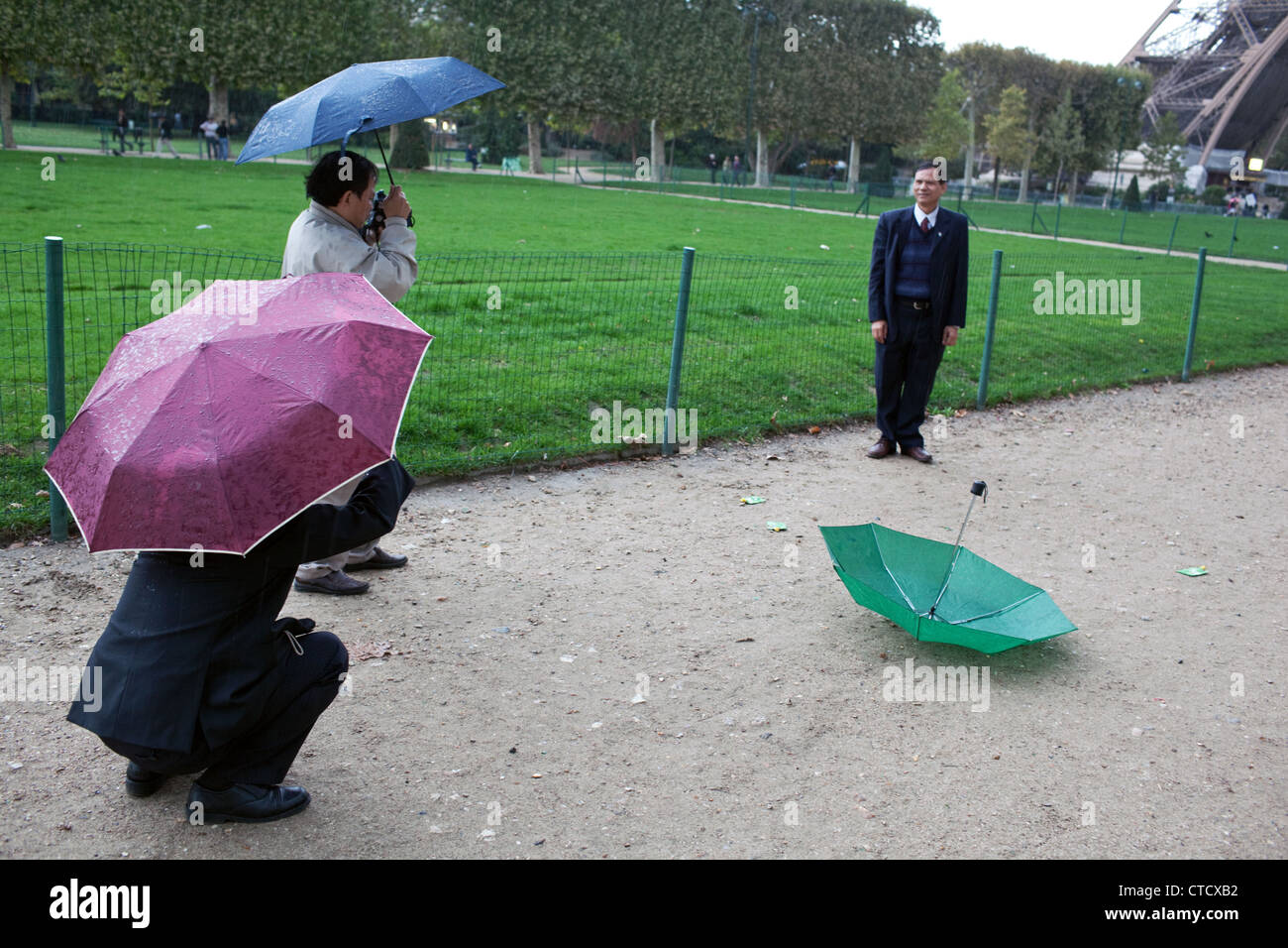 Visitatori asiatici comportano per le foto in "Parc du Champ de Marc - Campo di Marte' Torre Eiffel a Parigi. Foto Stock
