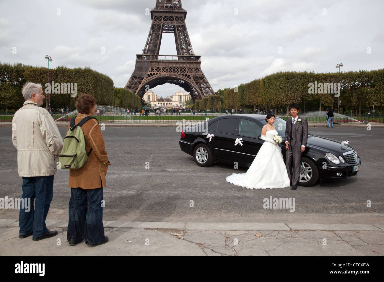 I turisti stranieri guardare una coppia cinese in posa per foto di matrimonio nel Campo di Marte vicino alla Torre Eiffel a Parigi, Francia. Foto Stock