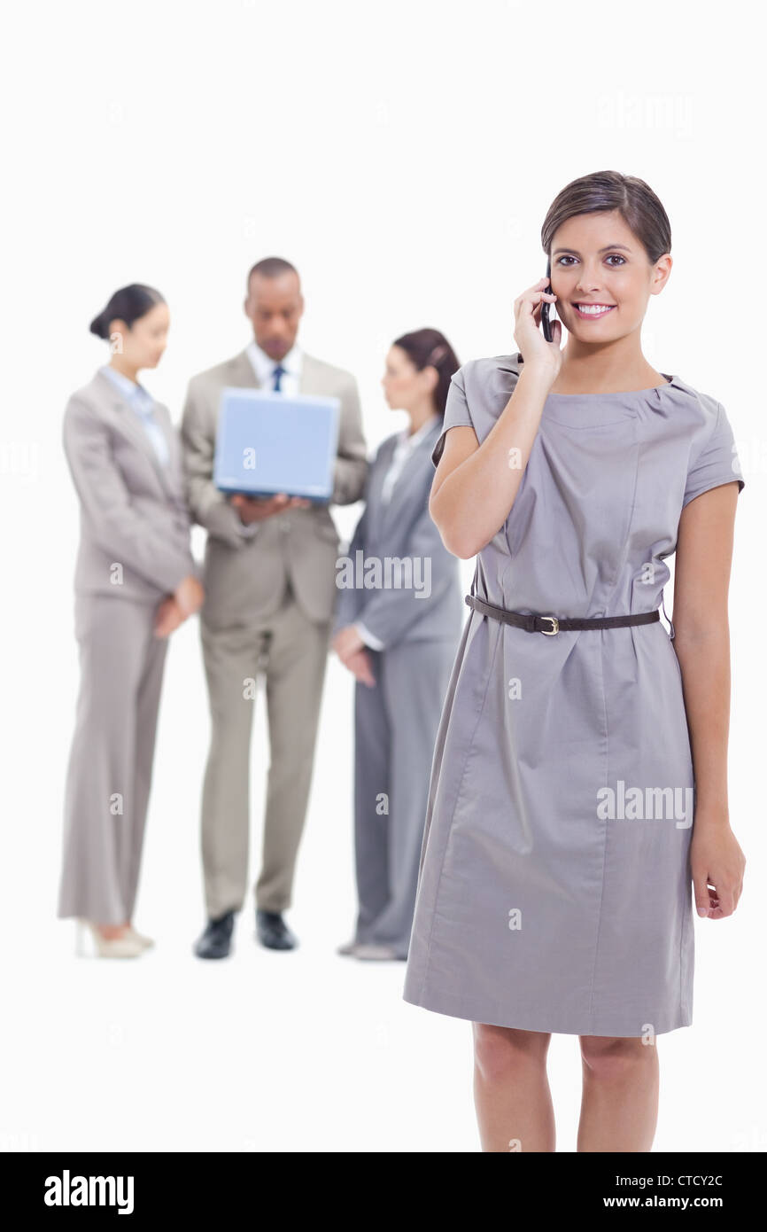 Imprenditrice sul telefono guardando dritto con un braccio lungo il suo corpo e la sua co-lavoratori nel Foto Stock