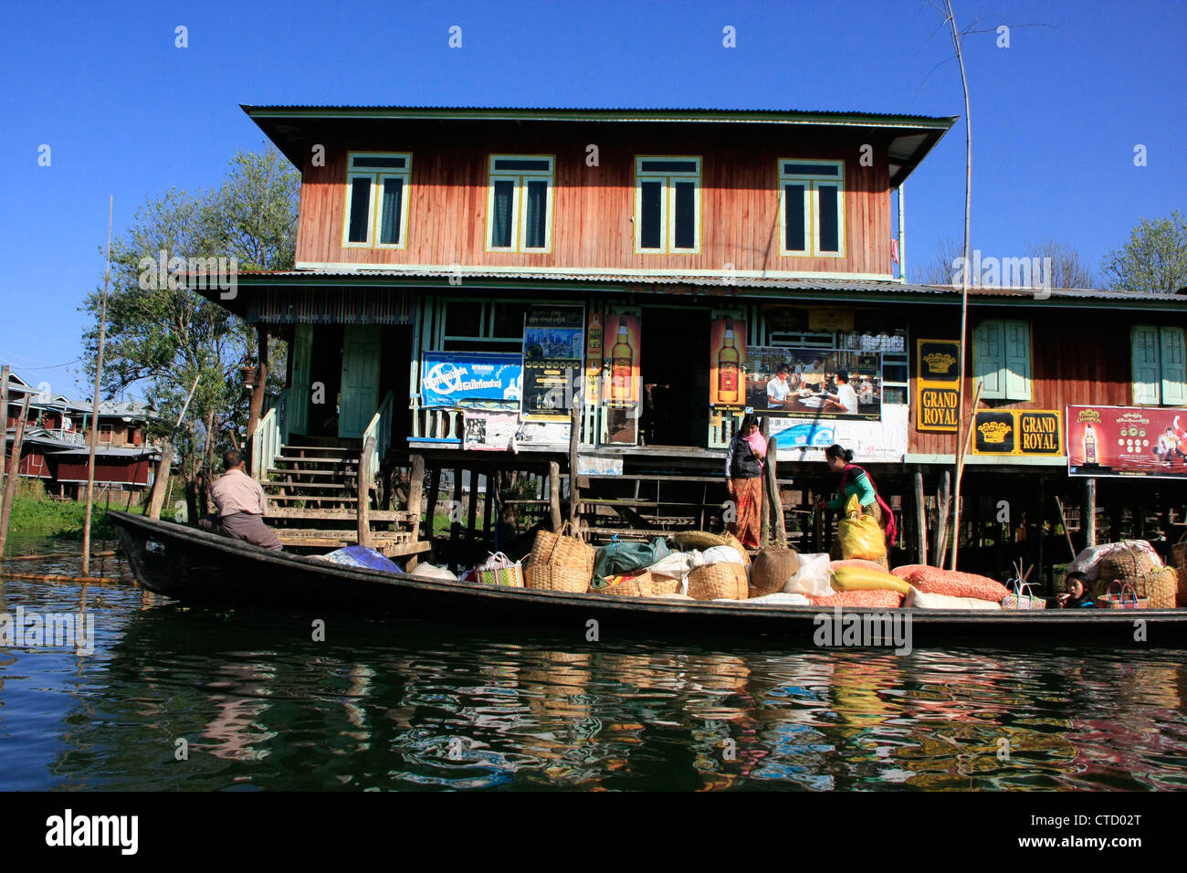 Popolo birmano lo scarico di merci da una barca, Lago Inle, stato Shan, Myanmar, sud-est asiatico Foto Stock