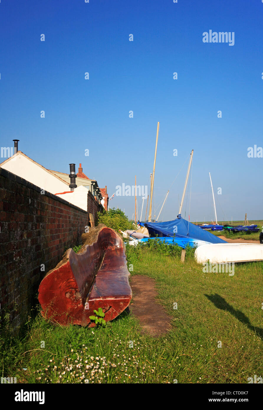 Una sede formata da un log e lucidato che si affaccia sul molo a Burnham Overy Staithe, Norfolk, Inghilterra, Regno Unito. Foto Stock