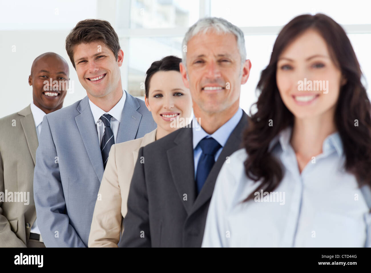 Tre sorridente la gente di affari nel contesto a seguito dei loro leader Foto Stock