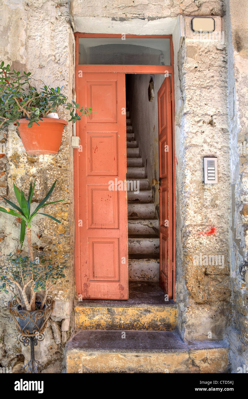 Orientata in verticale immagine della porta di legno e vecchi con scale strette nella piccola casa di città di Ventimiglia in Liguria, Italia. Foto Stock