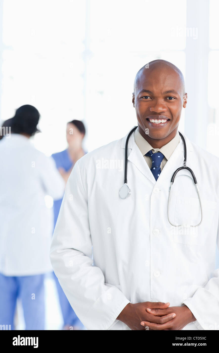 Giovane medico indossando una cravatta sotto il suo bianco camice Foto Stock