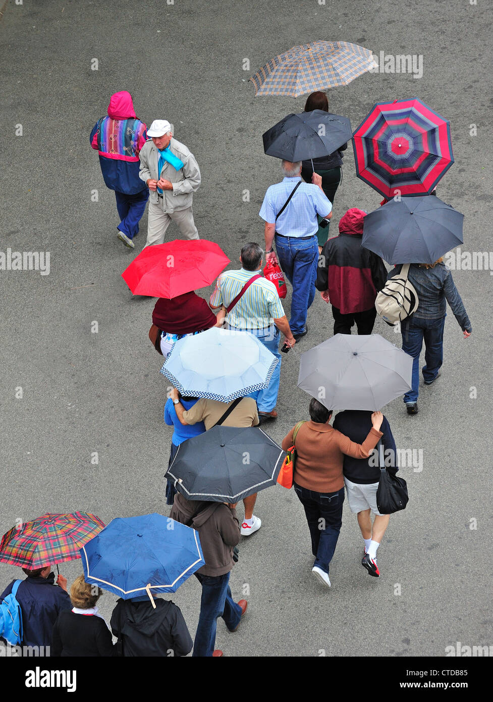 Persone con ombrelloni a piedi sotto la pioggia in una piovosa giornata umida in estate Foto Stock