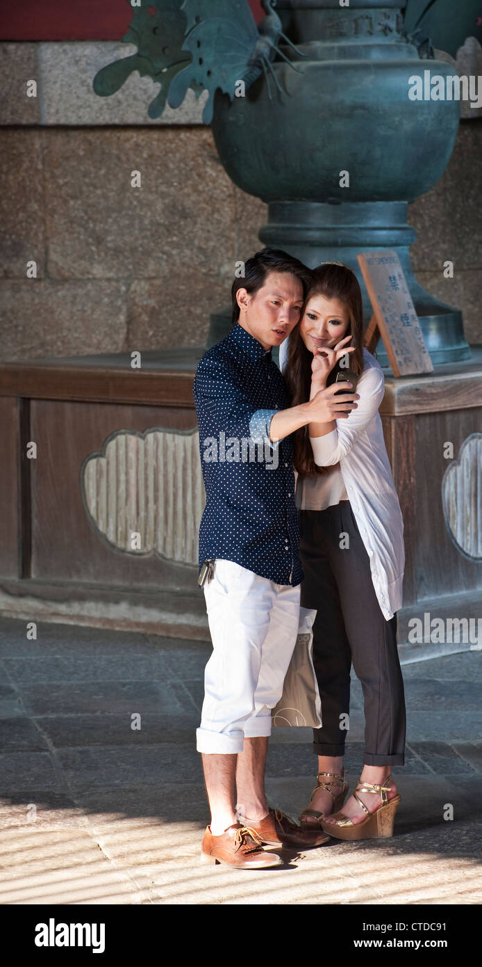 Una giovane coppia giapponese prende un selfie nella Sala del Grande Buddha (Daibutsuden) al tempio buddista di Todai-ji, Nara, Giappone Foto Stock