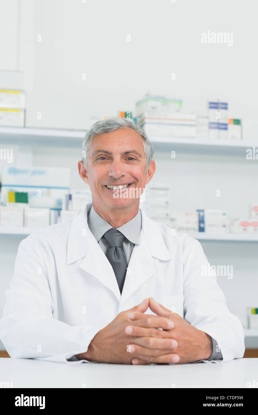 Sorridente farmacista maschio con le mani congiunte su un contatore Foto Stock