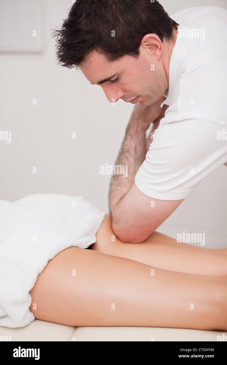 Massaggio chiropratico la coscia del suo paziente mentre si utilizza il suo gomito Foto Stock
