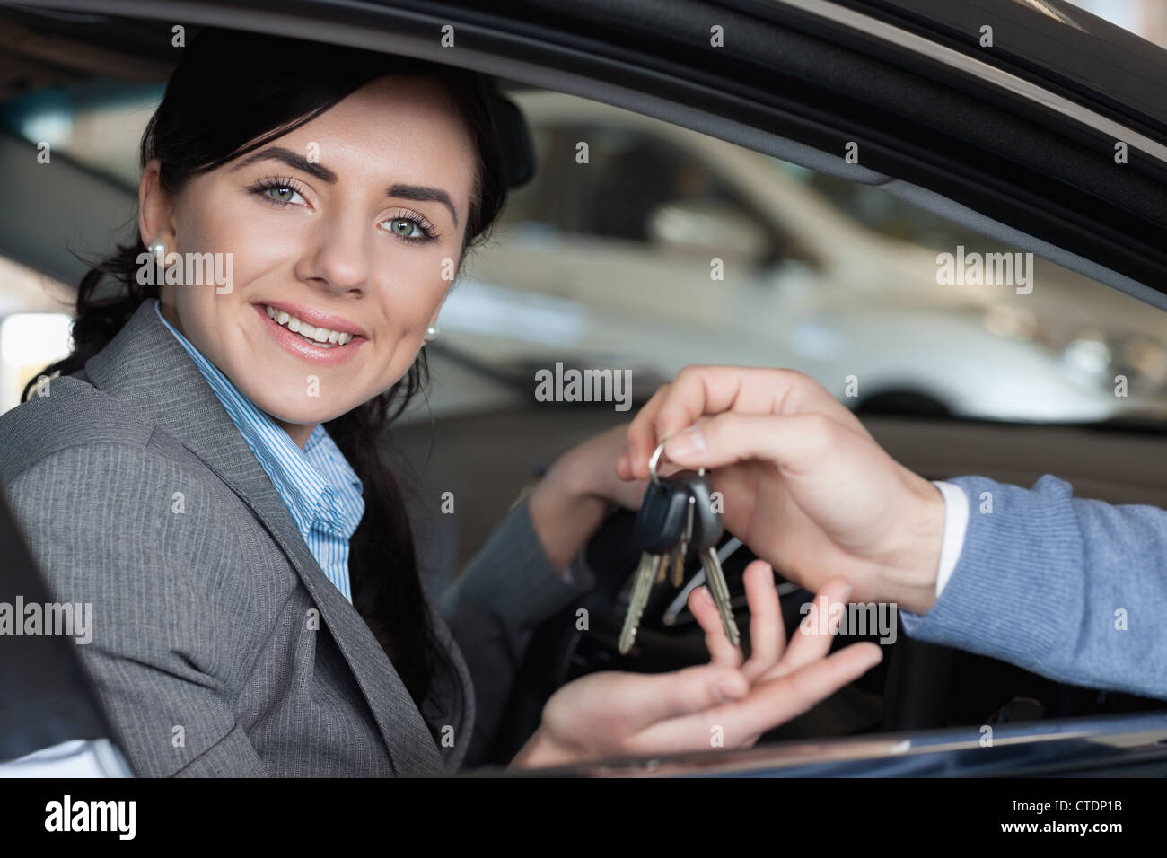 Donna sorridente in un auto di ricevere le chiavi dell'auto Foto Stock
