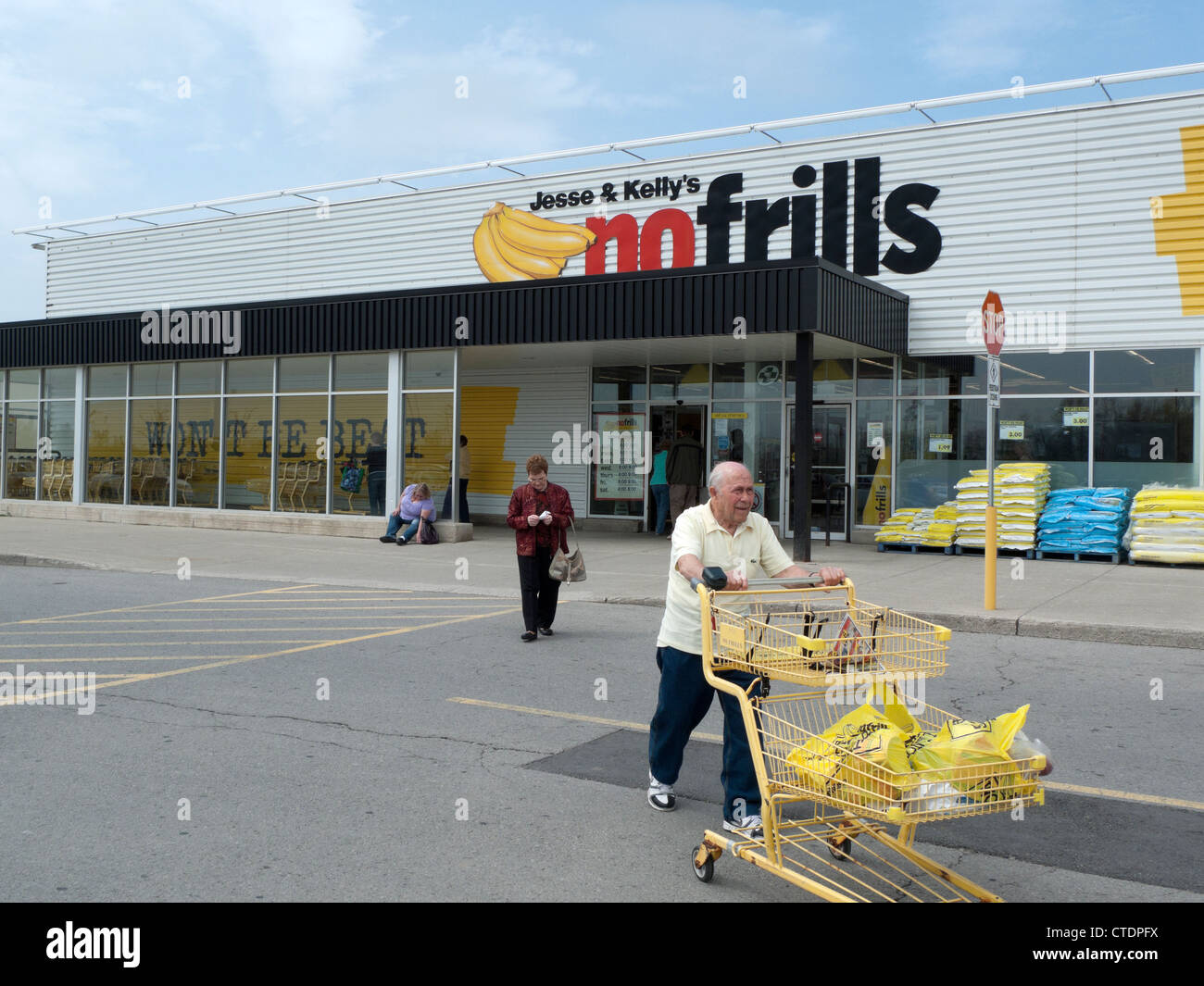 Un uomo anziano spingendo un carrello della spesa al di fuori di Jesse & Kelly senza fronzoli supermercato store Ontario, Canada, America del Nord Foto Stock