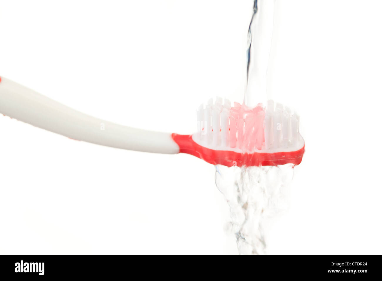 Acqua che cade su di uno spazzolino da denti in rosso Foto Stock