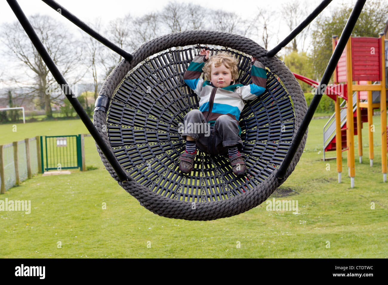 Quattro anni ragazzo biondo su un parco giochi basket swing Foto Stock