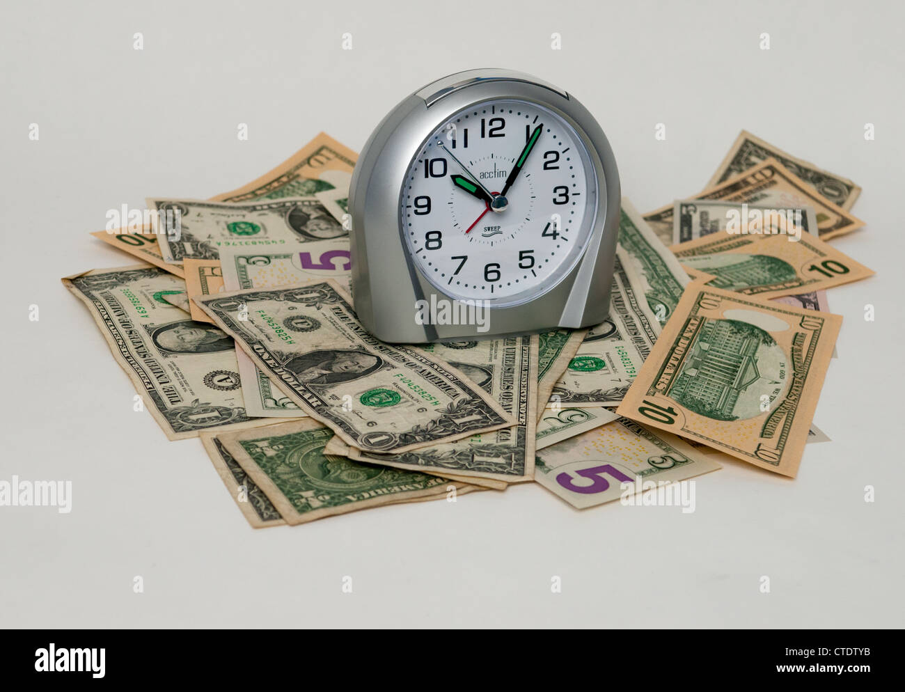 Un orologio seduto su un mucchio di soldi Foto Stock