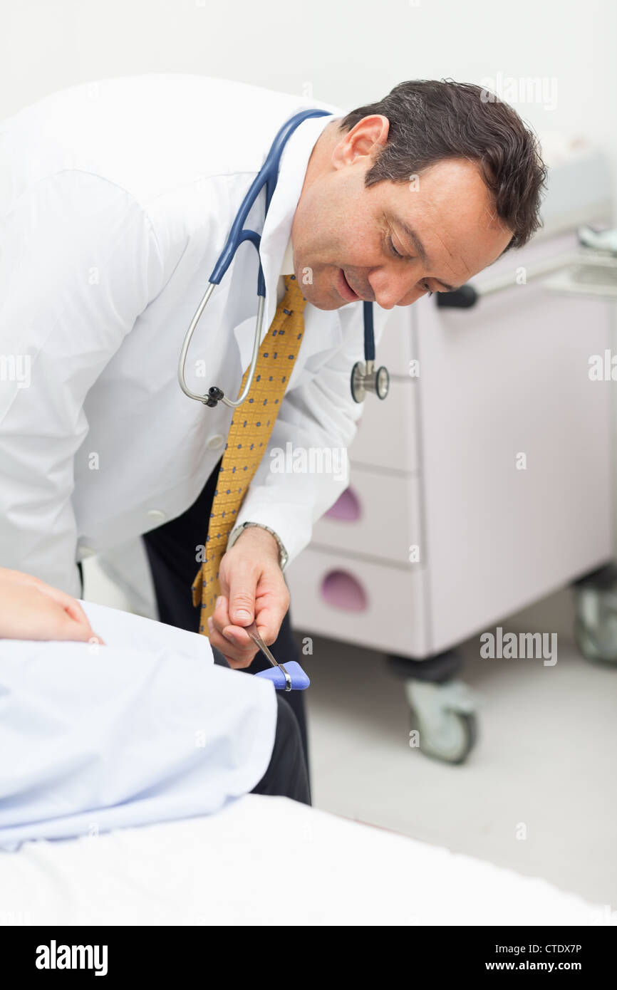 Controllo medico i riflessi del ginocchio di un paziente Foto Stock