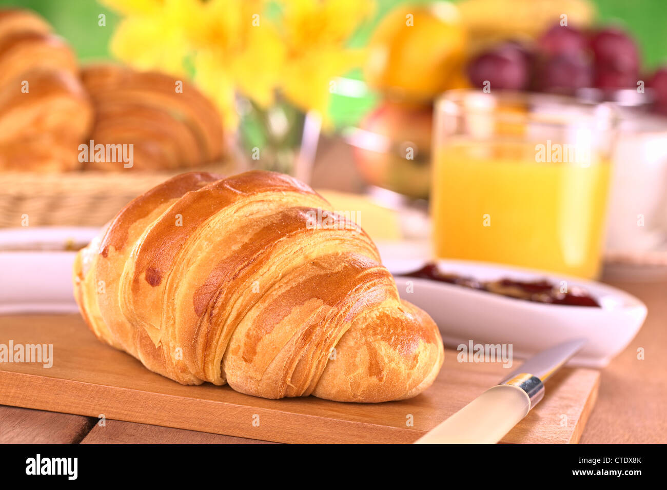 Croissant, marmellata, frutta e succo d'arancia a colazione (messa a fuoco selettiva, messa a fuoco sulla parte anteriore del croissant) Foto Stock