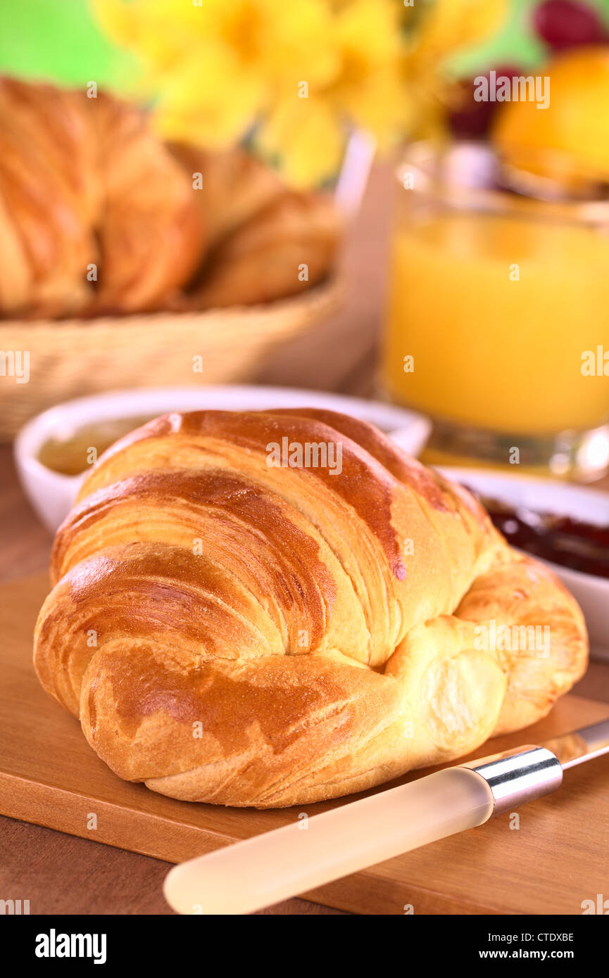 Croissant, marmellata, frutta e succo d'arancia a colazione (fuoco selettivo, la messa a fuoco di un terzo nel cornetto) Foto Stock