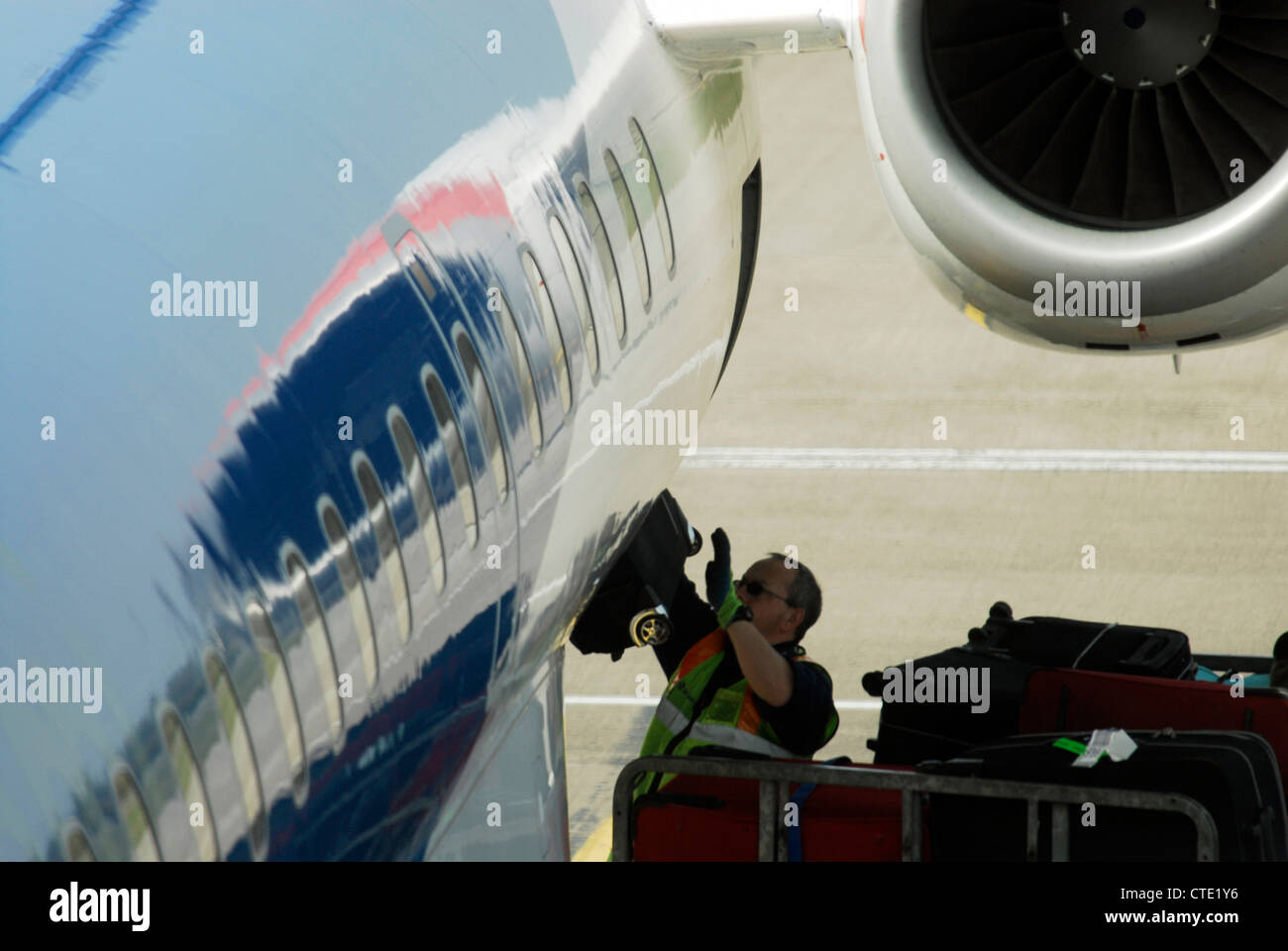 Un gestore di bagagli carichi di sacchetti scarica bagagli valigie per in  da un aereo all'aeroporto di Edimburgo Foto stock - Alamy