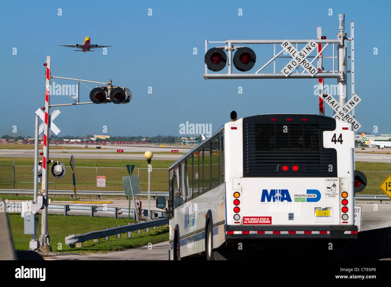 Boeing 737 in take off e un bus spento in corrispondenza di un incrocio ferroviario presso l'Aeroporto Internazionale di Miami, Florida, Stati Uniti d'America. Foto Stock