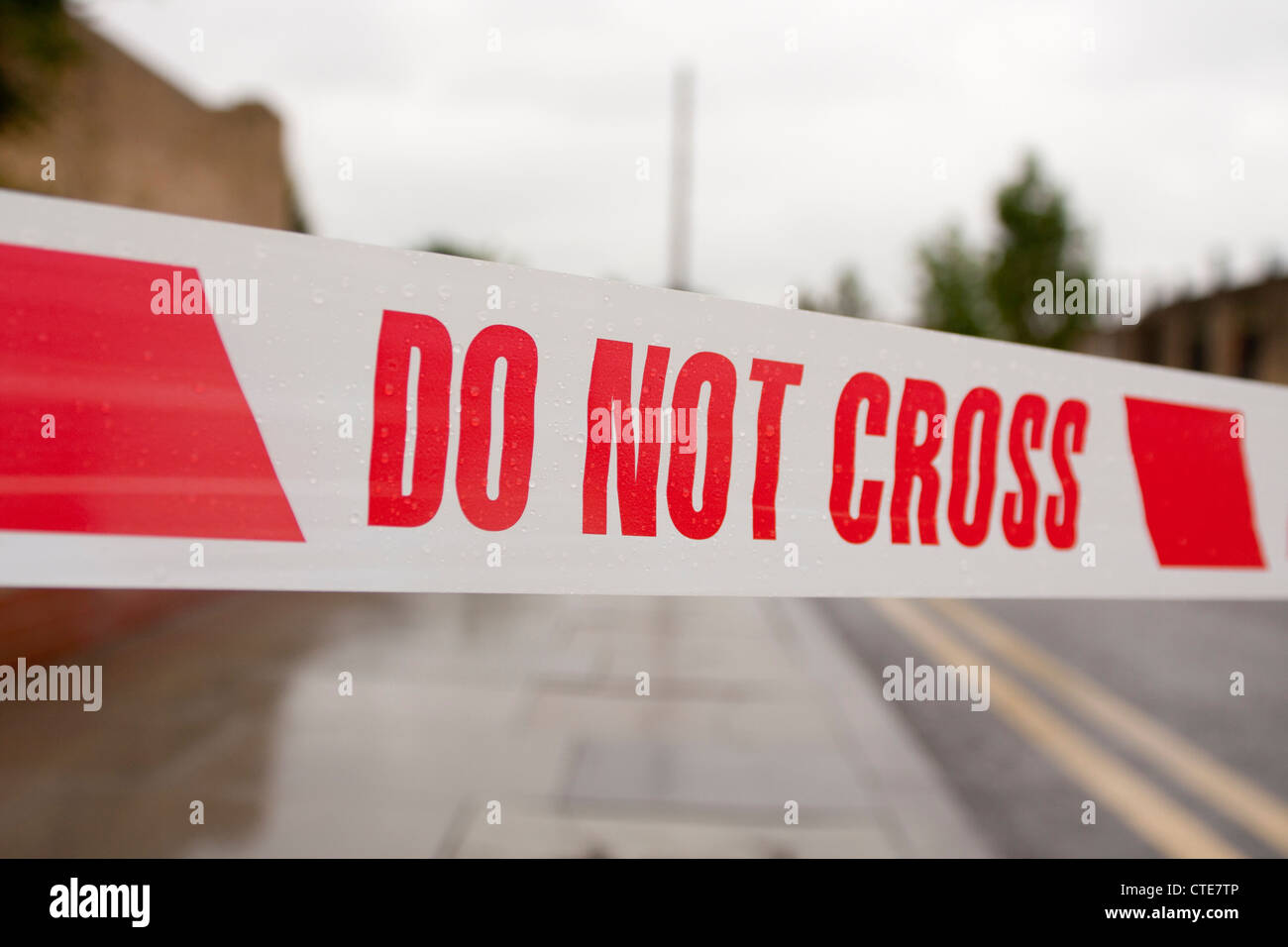 Nastro di polizia per la scena del crimine, 'non cross' rosso su bianco, generic sfondo sfocato con doppie linee di colore giallo Foto Stock