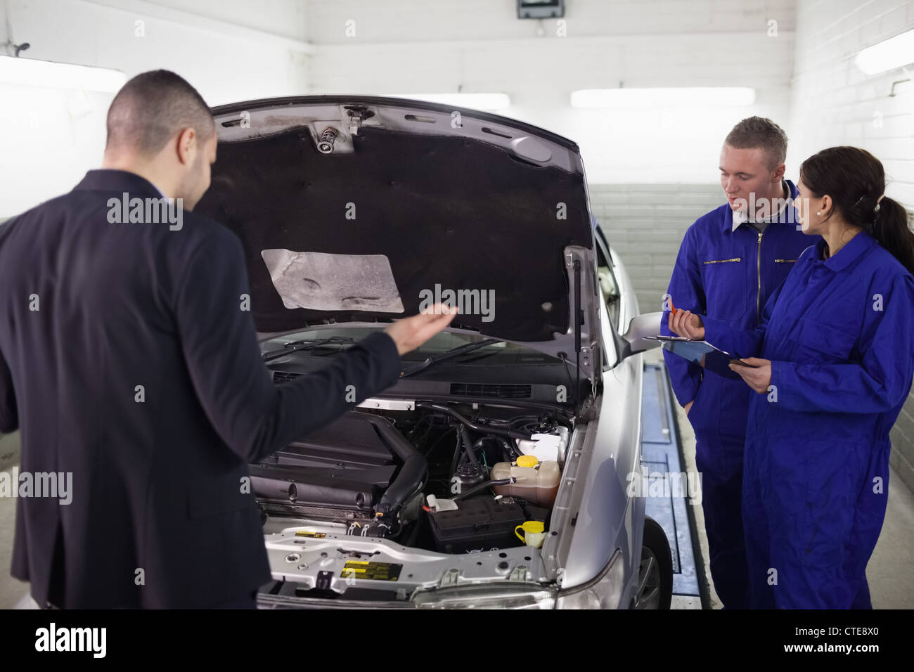 Client guardando un auto accanto alla meccanica Foto Stock