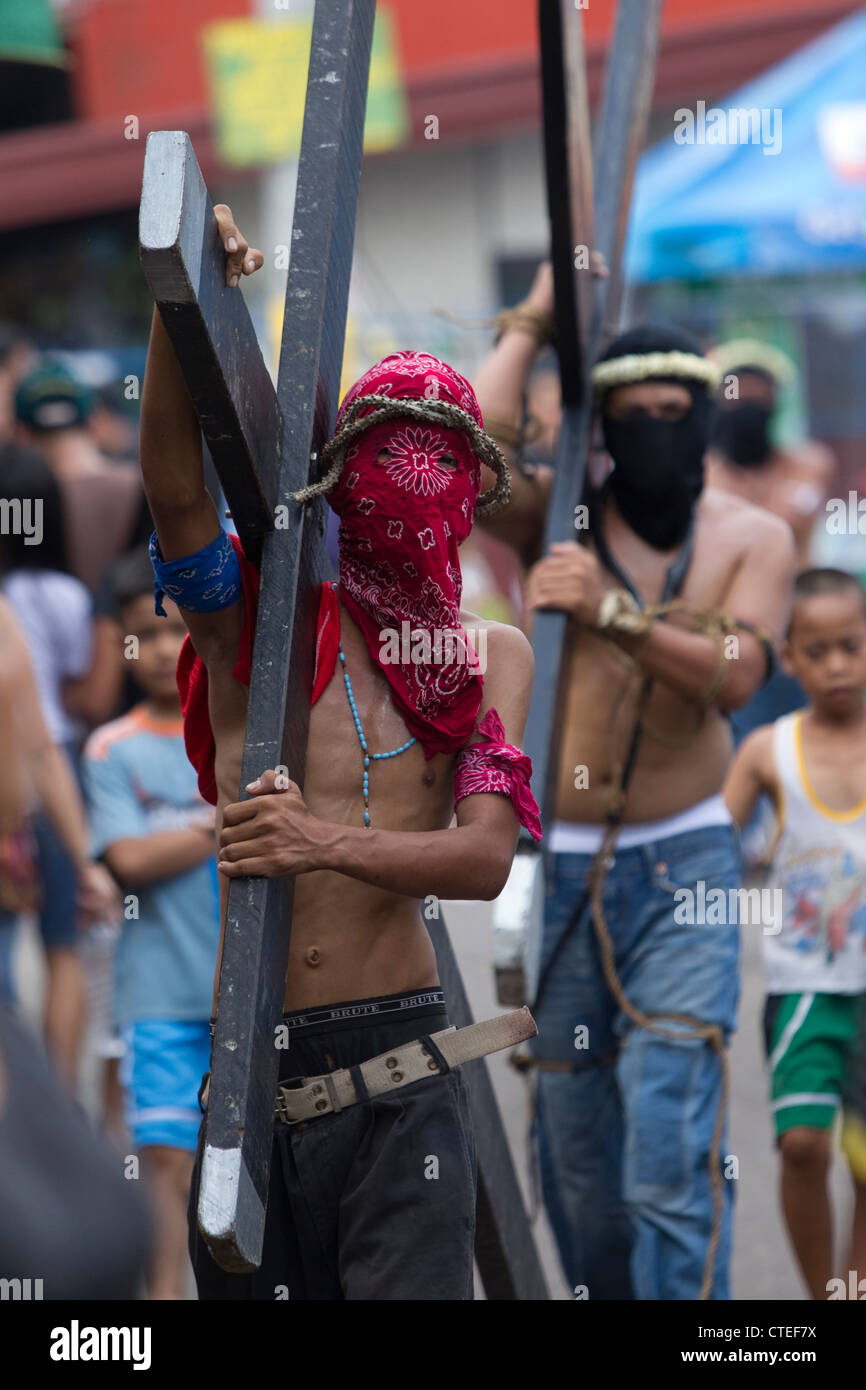 Uno dei vari penitenti portano una croce di legno del Giovedì Santo,Barangay Lourdes Northwest,Angeles City,Pampanga,Filippine Foto Stock