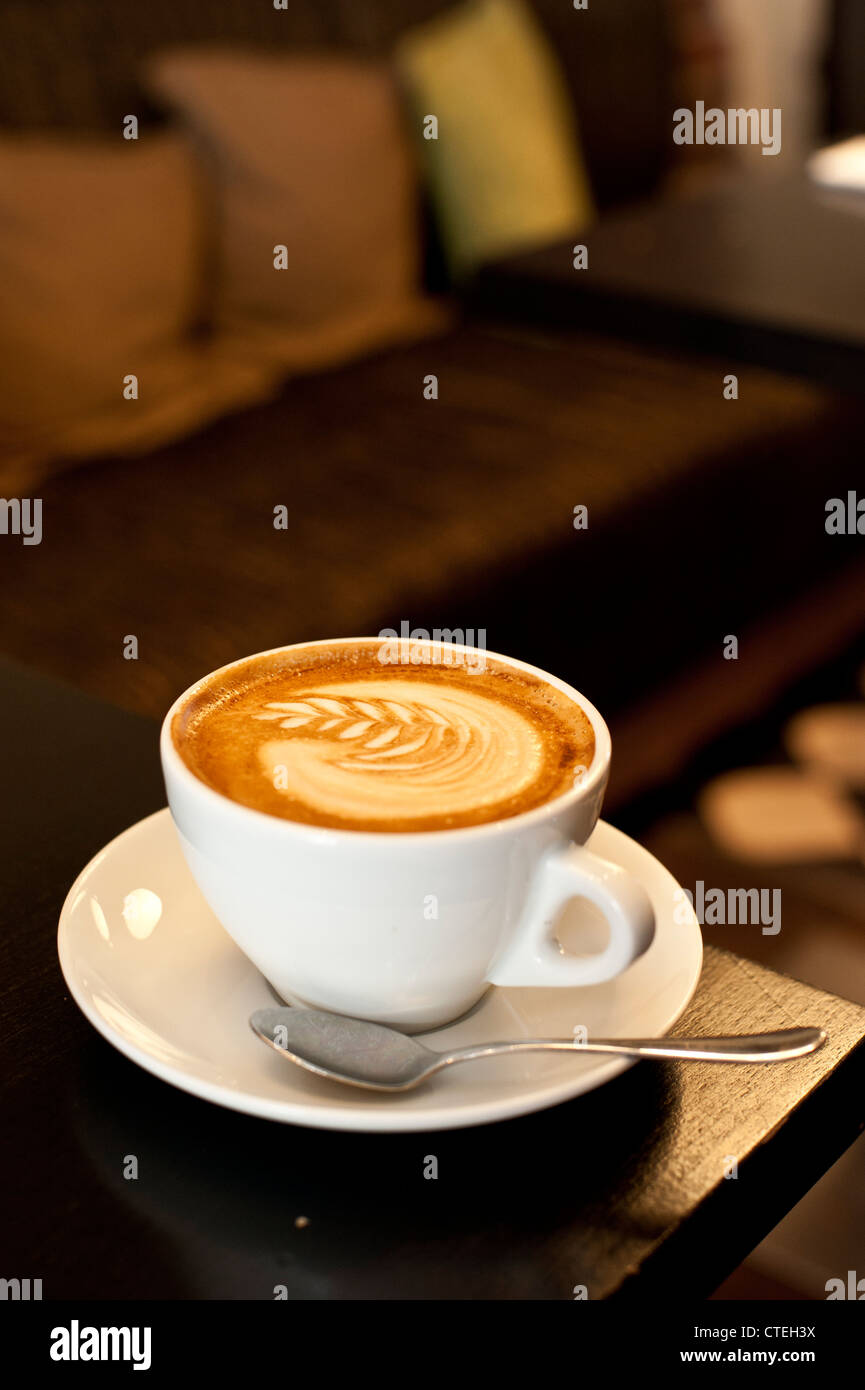 Tazza di cappuccino in un accogliente atmosfera illuminata Foto Stock