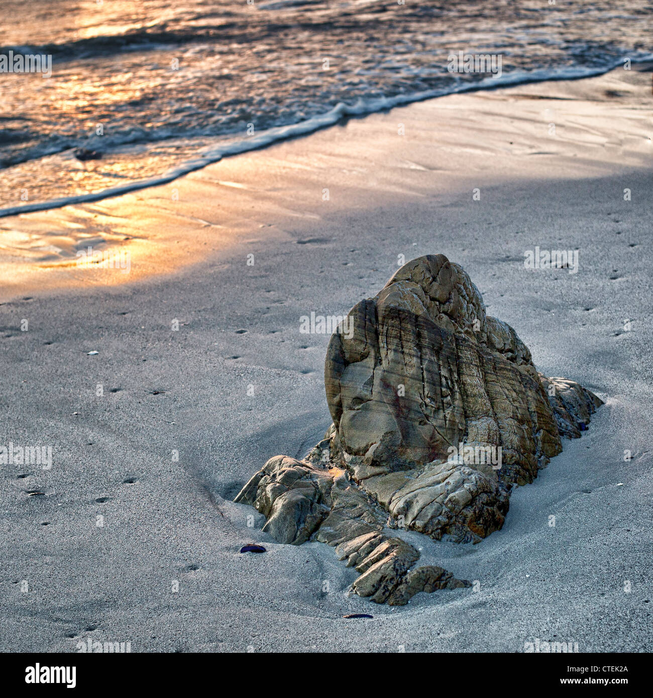 Una roccia solitaria sulla spiaggia al tramonto - Grotta Beach, Hermanus, Western Cape, Sud Africa Foto Stock