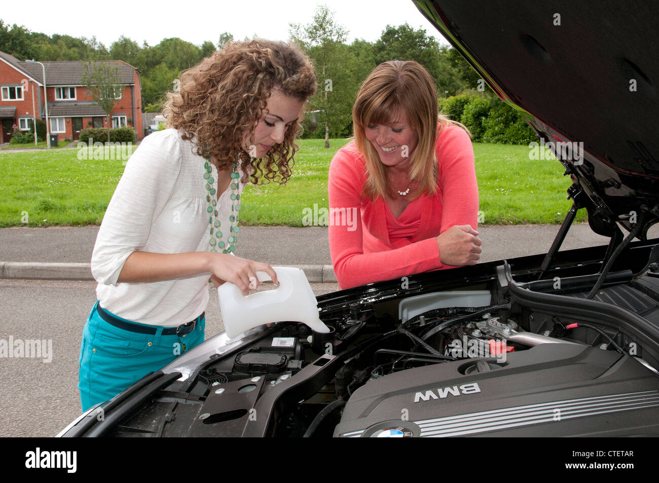 Il rabbocco del serbatoio di acqua per il lavaggio del parabrezza nel vano motore di un automobile Foto Stock